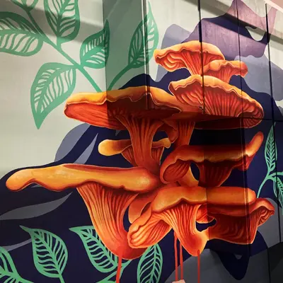 A vibrant, hand-painted mural on a modern geometric surface featuring large, vivid orange chanterelle mushrooms on a background of swirling deep purple and teal-blue leaves.